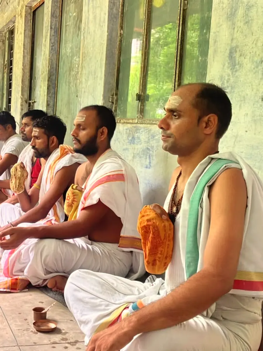 Priests seated in disciplined order along the Ashram corridor, performing rites in sequence