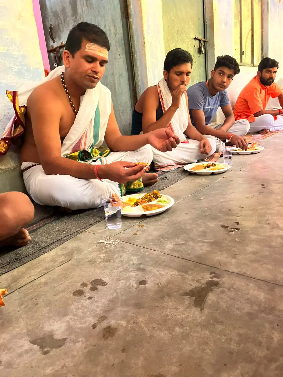 A priest performing Seva, feeding a cow as an act of selfless service