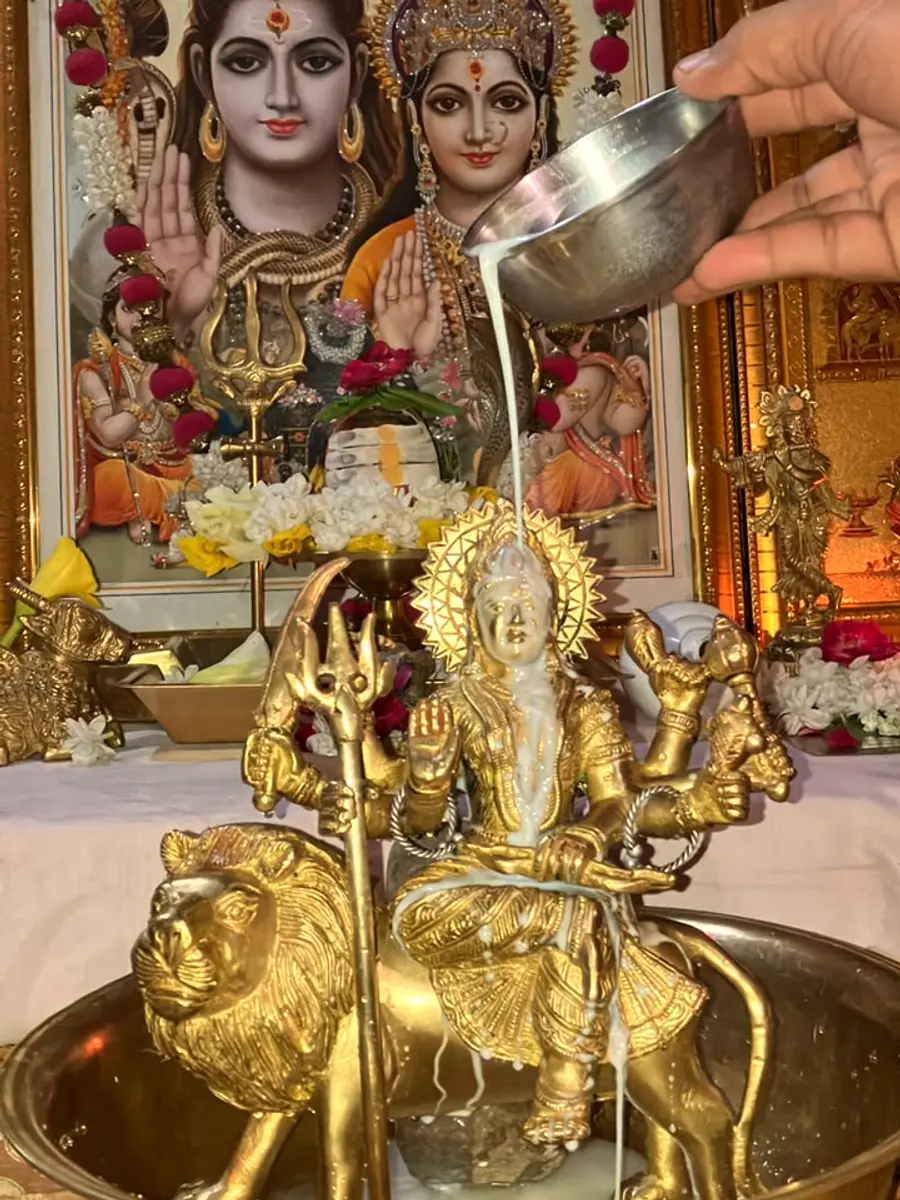 Milk abhishekam offered to a golden Durga murti as an act of devotion