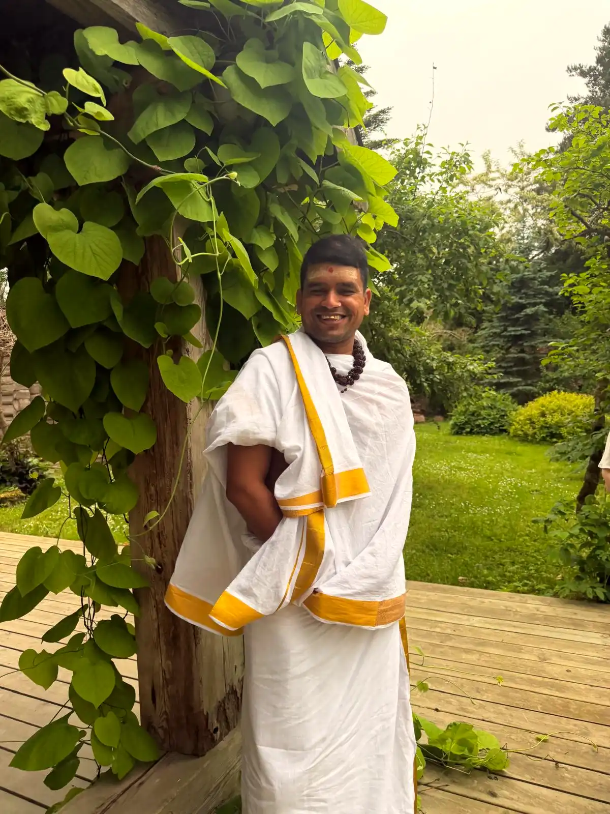 A smiling priest from Lakshmi Narayan Ashram warmly welcoming visitors